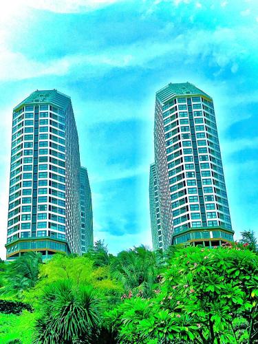 two tall buildings with palm trees in front of them at Seascape Mandala Resort Phan Thiết in Mui Ne