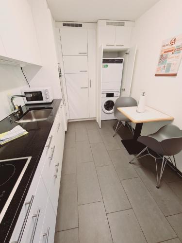 a kitchen with white cabinets and a table with chairs at Fantastic 2BD 110sqm Flat - Mainau 10 in Zürich