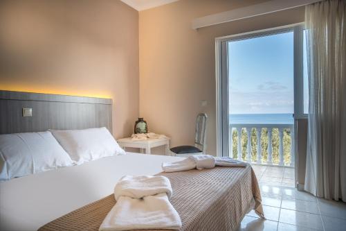 a bedroom with a bed and a large window with the ocean at Zakynthos Hotel in Tsilivi