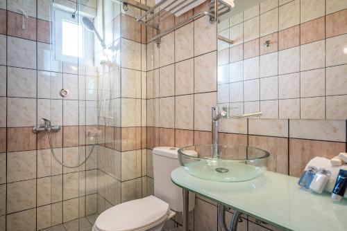 a bathroom with a toilet and a glass sink at Zakynthos Hotel in Tsilivi