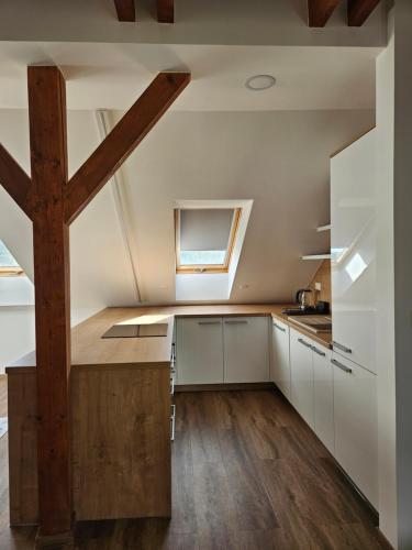an attic kitchen with white cabinets and a wooden beam at Brick House Residence in Poprad