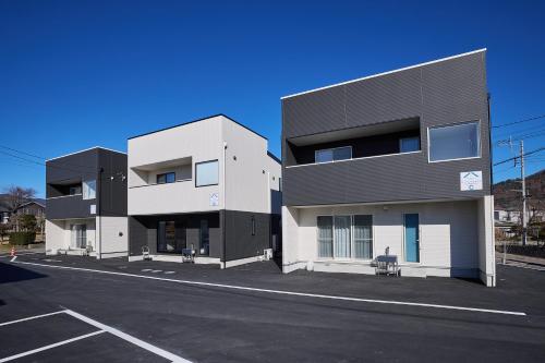 a black and white building with a parking lot at MIYA HOUSE Funatsu B in Fujikawaguchiko