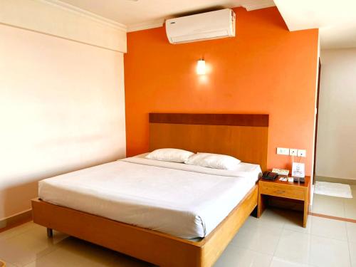 a bedroom with a bed with an orange wall at Hyson heritage calicut in Kozhikode