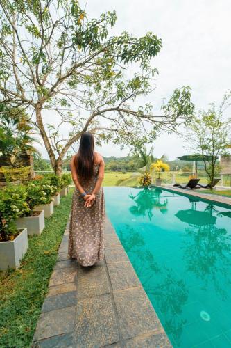 a woman in a dress standing by a swimming pool at The Quale Villa in Galle