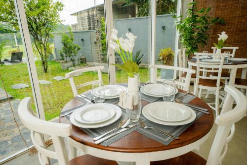 a wooden table with white plates and silverware on it at The Quale Villa in Galle