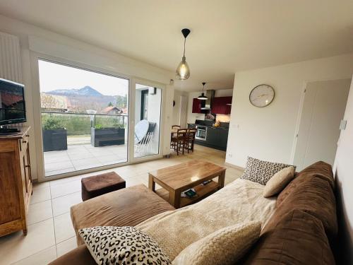 a living room with a couch and a large window at Bel appartement proche du lac in Duingt