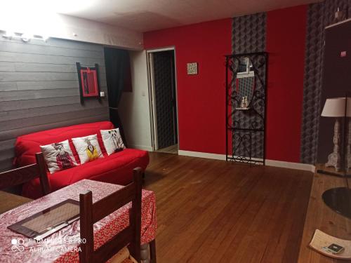 a living room with red walls and a red couch at Havre de paix au bords de l'Eure - divers hébergements in Neuilly