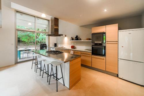 Il comprend une cuisine équipée d'un réfrigérateur blanc et d'un comptoir avec tabourets. dans l'établissement Villa HOUX & IVY 3 chambres proche Lac Marin rive est -Wifi #0384, à Hossegor