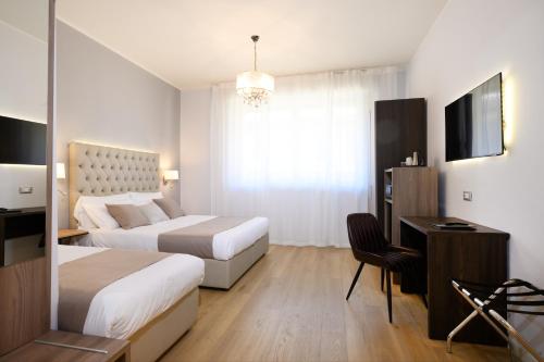 a hotel room with two beds and a desk and a television at Domus Uffizi in Florence