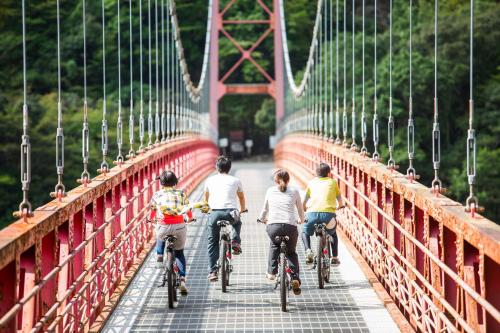 a group of people riding bikes across a bridge at 宿屋まてまて Villa Mate Mate in Sawara