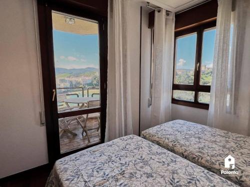 a bedroom with two beds and a window with a view at FN231 El Cuco in San Vicente de la Barquera