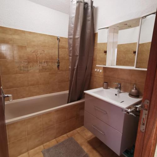une salle de bain avec un lavabo, une baignoire et un miroir dans l'établissement Les Campanules-Centre station, à Risoul