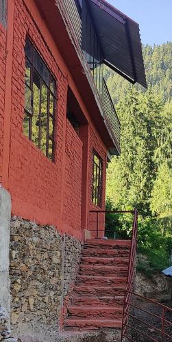 a red house with a staircase in front of it at Ekaant Orchard Retreat , A Serene Homestay in Nārkanda