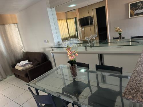a living room with a glass table with a vase of flowers at Apartamento Beira Mar Fortaleza Beach Class in Fortaleza
