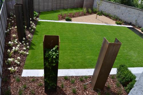 a garden with green grass and wooden sculptures at B&B L'Echappée Belle Welness Spa et Table d'hôtes in Falaën