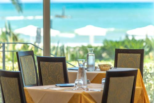 a table with a yellow tablecloth and chairs with the ocean at Roses Hotel in Roseto degli Abruzzi