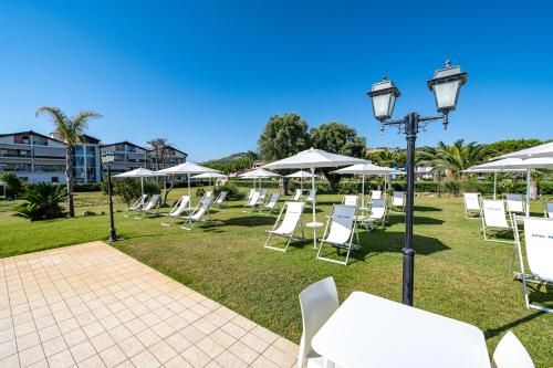 a row of white chairs and tables with umbrellas at Roses Hotel in Roseto degli Abruzzi