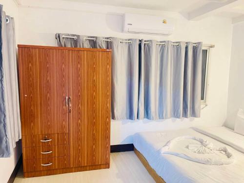 a bedroom with a wooden cabinet next to a bed at Lamoon Center Point in Hat Yai