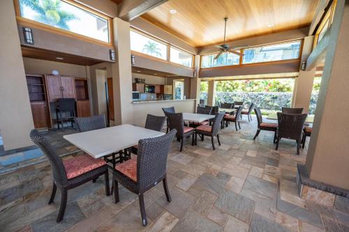 a dining room with tables and chairs and windows at Elua 406 in Wailea