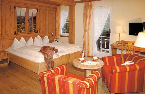 a bedroom with a bed and two chairs and a table at Schwarzwaldhotel Klumpp in Baiersbronn