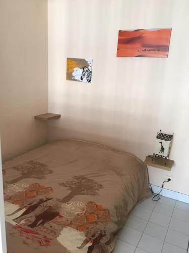 - un lit dans une chambre avec 2 photos sur le mur dans l'établissement Fréjus, 200 m des plages appart f1 avec piscine, à Fréjus