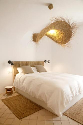 a bedroom with a large white bed and a chandelier at Maram Brava casa centro Begur Metge Pi in Begur