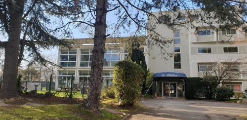 un immeuble de bureaux avec des arbres devant dans l'établissement Studio Carquefou, à Carquefou