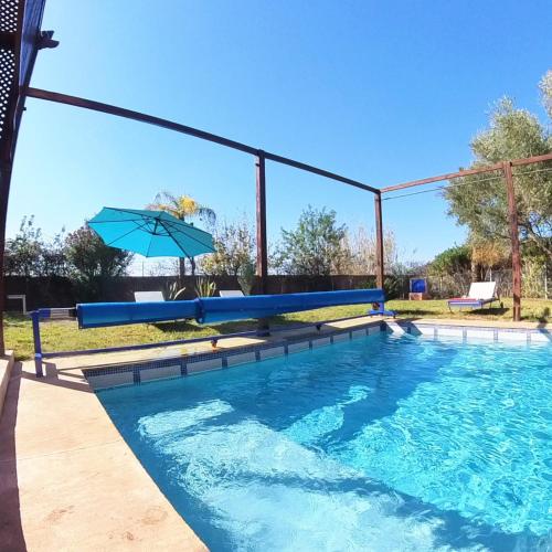 a swimming pool with an umbrella and a swimming pool at Villa Belle vue - with a private & Heated pool in Marrakesh