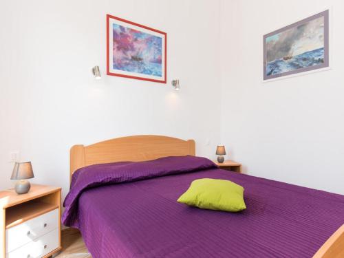 a bedroom with a purple bed with a yellow pillow at Apartments Josip in Čižići