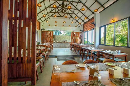 a restaurant with wooden tables and chairs and windows at Vbrings Oak Village in Munnar