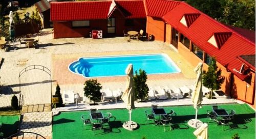 a swimming pool with chairs and a red roof at Pensiunea Privighetoarea in Potoceni