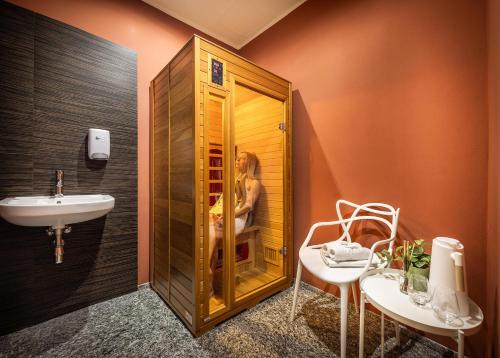 a bathroom with a sink and a shower with a woman in it at Omnia Hotel Relax & Wellness in Janske Lazne
