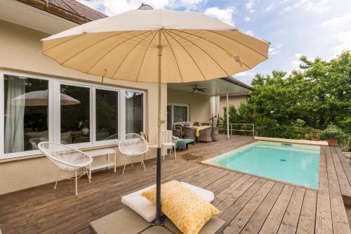 an umbrella sitting on a deck next to a pool at Elegant Pool Bungalow - Vienna City Limit in Hennersdorf