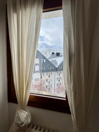 a window with white curtains and a view of a building at Rincón de Anayet Entrada Autónoma Formigal in Formigal