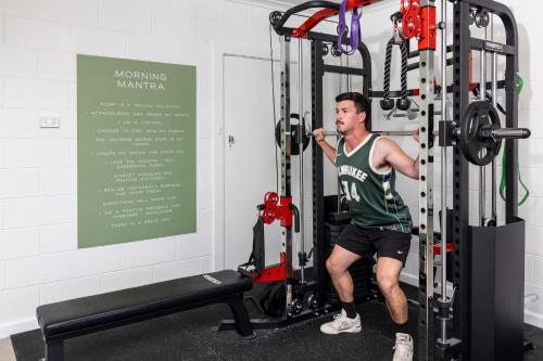 a man in a gym doing a squat in a squatting machine at Barossa Palms Motel in Nuriootpa