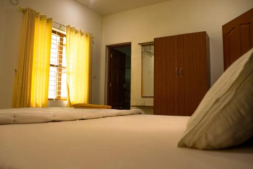 a bedroom with a large white bed with a window at Chakkantharas Pool Villas in Athirappilly