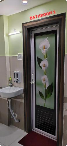 a bathroom with a glass door with a flower on the wall at LN BEACH Homestay in Puri