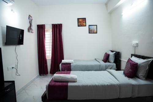 a hotel room with two beds and a tv at Yellow Bells Serviced Apartments Hitech City in Kondapur