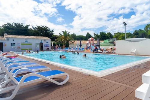 una gran piscina con sillas y gente en ella en Camping 4 étoiles - Parc aquatique - eeibci, en Le Bois-Plage-en-Ré