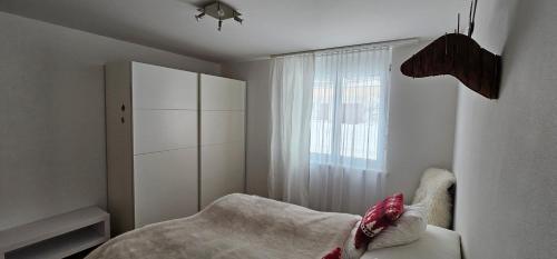 a white bedroom with a bed and a window at Casa a Sulegl in Savognin