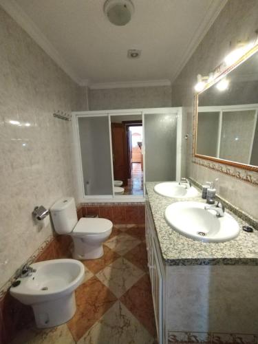a bathroom with two sinks and a toilet and a mirror at Casamanuela in Aracena