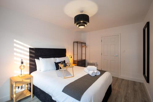 a bedroom with a large white bed with a night stand at Watford 2-Bed Oasis - 20-min to London - Central in Watford