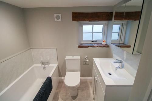 a bathroom with a tub and a toilet and a sink at South View Cottage Dacre in Dacre