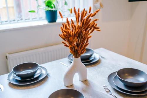 a table topped with plates and a vase with wheat at K Suites - Hollins Road in Oldham