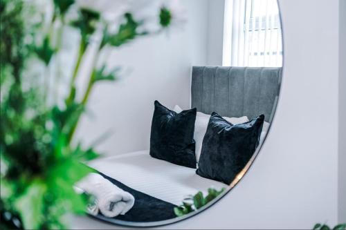 a mirror reflecting a chair with pillows on it at K Suites - Hollins Road in Oldham