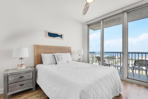 a white bedroom with a bed and a balcony at Emerald Dolphin unit 650 in Pensacola Beach