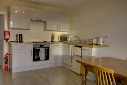 a kitchen with white cabinets and a wooden table at Tigh-na-mara, Helmsdale in Helmsdale