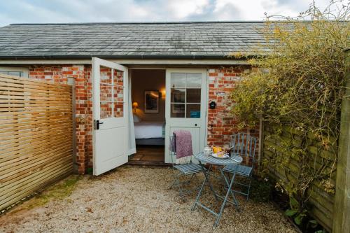 a brick house with a door and a table and chairs at Crepe Farm Barns in Bridport