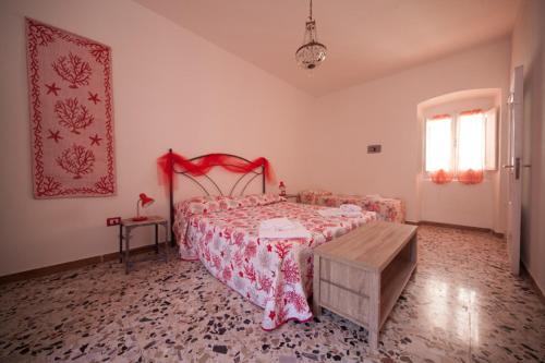 Schlafzimmer mit einem Bett mit einer roten Tagesdecke in der Unterkunft Il Corallo E La Quercia Apartment in Villanova Monteleone