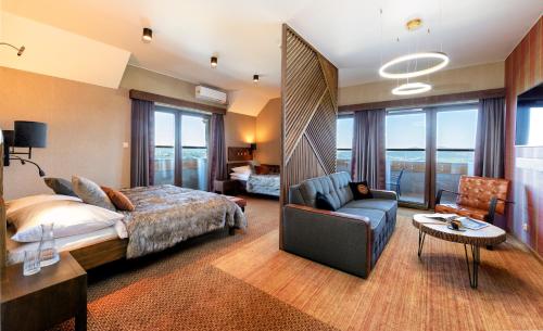 a bedroom with a bed and a couch and a chair at Złoty Groń Resort & Spa in Istebna